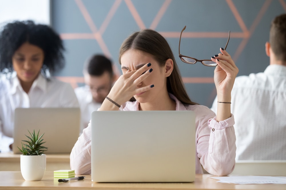 A woman struggling with dry eye syndrome at work