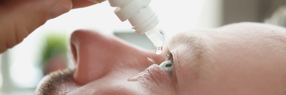 Man using eye drops to treat dry eyes from Computer Vision Syndrome