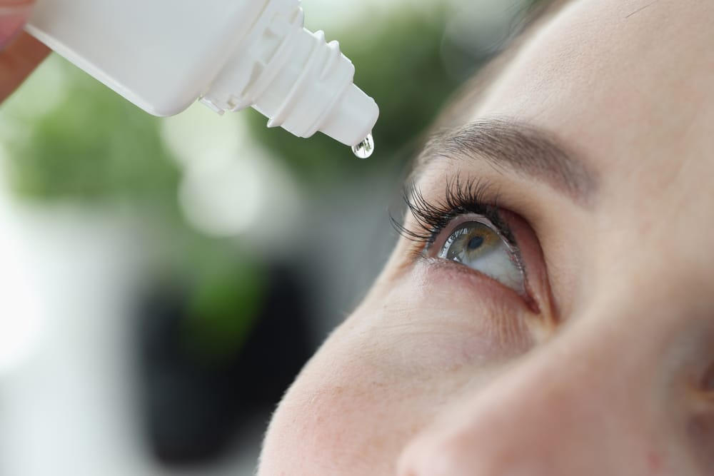 woman putting eye drops in her eyes as allergy season in nashville affects her eyes