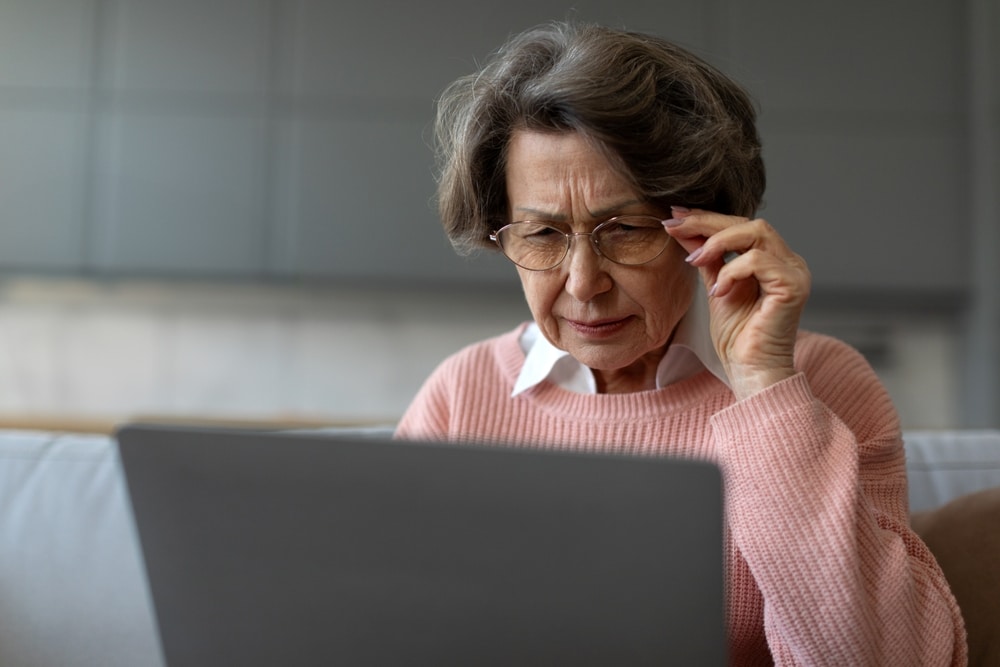Is macular degeneration hereditary, or is it the result of age and other factors? Elderly woman struggles to see a computer